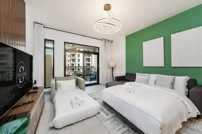 a bedroom with two beds and a green wall at Asayel Apartments in Dubai