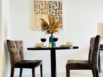 a table with two chairs and a table with wine glasses at Top Floor Luxurious Apt in JVC, Near Marina in Dubai