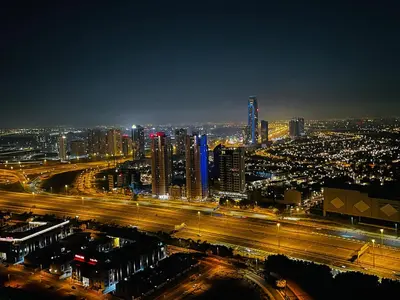 a city lit up at night with traffic on a highway at Top Floor Luxurious Apt in JVC, Near Marina in Dubai