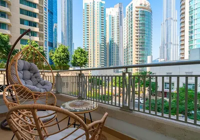 a balcony with chairs and tables and a city skyline at Luxurious 2-bedroom Apartment in Downtown with Burj Khalifa View in Dubai