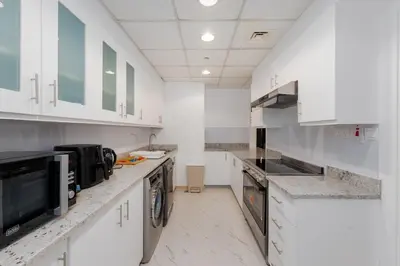 a large white kitchen with white cabinets and appliances at Sadaf 5, Jumeirah Beach Residence, JBR - Mint Stay in Dubai