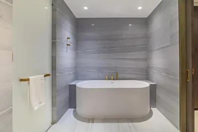 a bathroom with a white tub and gray walls at Luxury 3BDR Apartment, Pool & Beach Access in Dubai