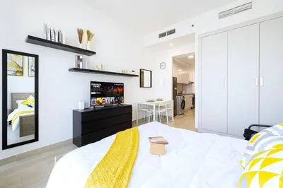 a bedroom with a large white bed with a yellow blanket at Lovely Studio in Bloom Tower, 10 minutes to Marina in Dubai