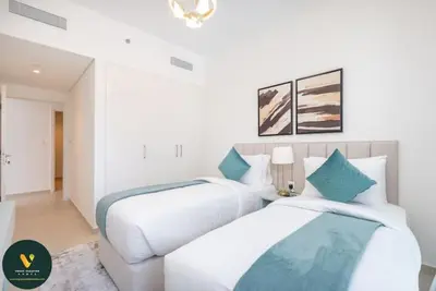 two beds in a room with white walls and blue pillows at Vogue Downtown Views II with Direct Access to Dubai Mall Via a Climate Controlled Bridge, Three Bedroom Apartment plus kids room and Balcony with Burj Khalifa View in Dubai