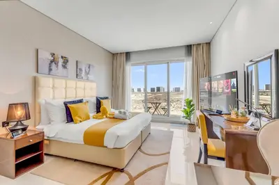 a bedroom with a large bed and a desk with a computer at Waves - Stylish Studio with Balcony in Dubai South in Dubai