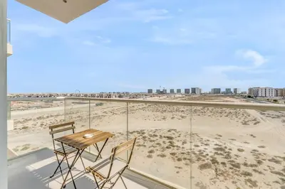 a table and chairs on a balcony with a view of the beach at Waves - Stylish Studio with Balcony in Dubai South in Dubai