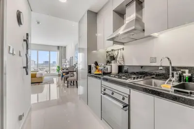 a white kitchen with a sink and a stove at Waves - Stylish Studio with Balcony in Dubai South in Dubai