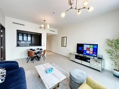 a living room with a blue couch and a tv at Modern Elegance in Downtown 1BR with Luxe Decor by Petals Holiday Homes in Dubai