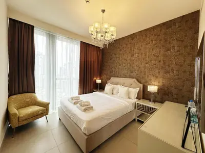 a bedroom with a bed and a chair and a chandelier at Modern Elegance in Downtown 1BR with Luxe Decor by Petals Holiday Homes in Dubai