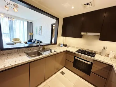 a kitchen with brown cabinets and a sink and a window at Modern Elegance in Downtown 1BR with Luxe Decor by Petals Holiday Homes in Dubai