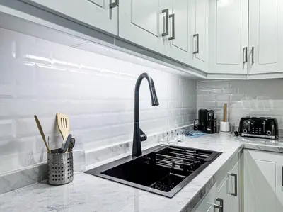 a kitchen with white cabinets and a stove top oven at DreamShoma -1B Spacious Apartment with a Lake View in Dubai