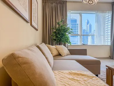 a living room with a couch and a large window at DreamShoma -1B Spacious Apartment with a Lake View in Dubai
