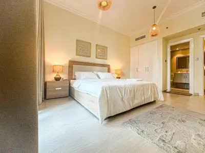 a bedroom with a large white bed and a table with lamps at DreamShoma -1B Spacious Apartment with a Lake View in Dubai