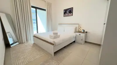 a white bedroom with a bed and a window at Sleek 1BR in DSO, Dubai in Dubai