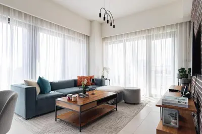 a living room with a blue couch and a table at Arthouse Royale - 2BR with Burj Khalifa Views, Swimming Pool & Gym in Dubai
