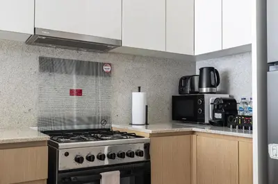 a kitchen with a stove and a microwave at Arthouse Royale - 2BR with Burj Khalifa Views, Swimming Pool & Gym in Dubai