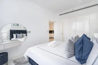a white bedroom with a large bed and a mirror at DownTown, Amazing Business Bay Skyline Views in Dubai