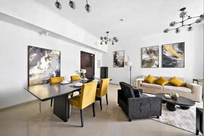 a living room with a dining room table and yellow chairs at Newly-furnished 1BR at DEC Tower 2 in Dubai