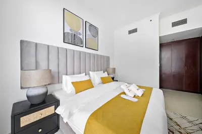 a bedroom with a large bed with a yellow blanket at Newly-furnished 1BR at DEC Tower 2 in Dubai
