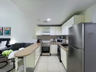 a kitchen with white cabinets and a stainless steel refrigerator at Lovely Studio at The Arch Tower JLT in Dubai