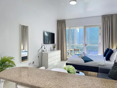 a bedroom with a bed and a living room at Lovely Studio at The Arch Tower JLT in Dubai