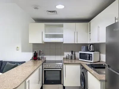 a kitchen with white cabinets and a counter top at Lovely Studio at The Arch Tower JLT in Dubai