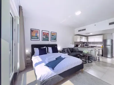 a bedroom with a bed and a living room at Lovely Studio at The Arch Tower JLT in Dubai