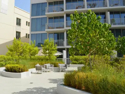 a building with chairs and a tree in front of it at Chic Modern Studio in Luma21, Best Pool & Gym in JVC Dubai in Dubai