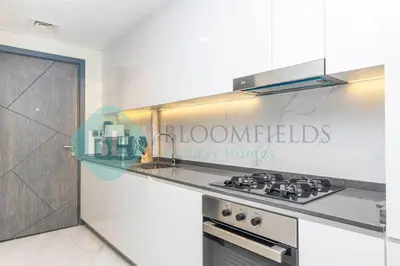 a kitchen with a stove top oven next to a counter at Bloomfields Luxury Escape Studio In Samana Golf in Dubai