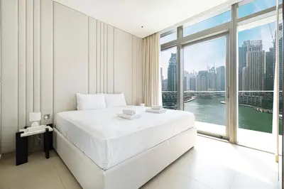 a bedroom with a white bed and a large window at 3BR Full Marina View for 8 Near The Metro! in Dubai
