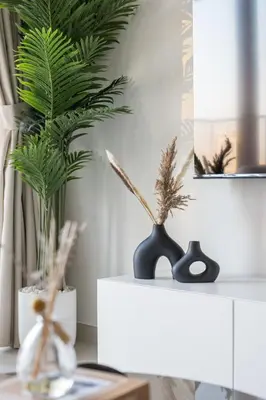 a table with two vases and a plant on it at Elegant 2BR in Burj Royale in Dubai
