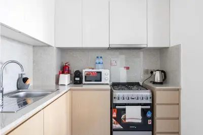a kitchen with white cabinets and a stove top oven at Elegant 2BR in Burj Royale in Dubai
