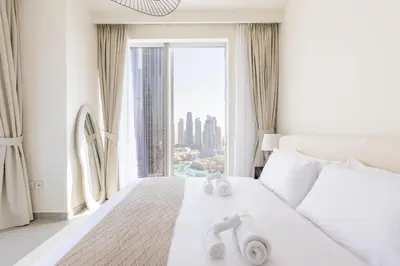 a bedroom with a white bed with a large window at Luxury 3BR and Maid room Forte Tower 1 with Fountain View in Dubai