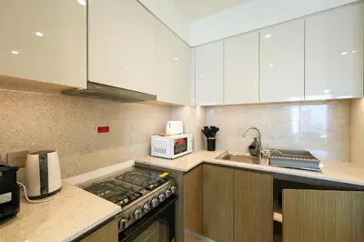 a kitchen with white cabinets and a stove top oven at Stunning 2BR Apt Burj Royale 10 mins walk to Dubai mall in Dubai