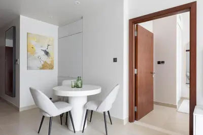 a white dining room with a white table and chairs at Cosy Apartment Marina Gate in Dubai