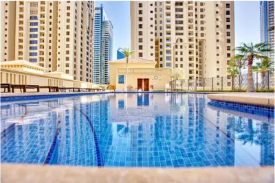 a large swimming pool in a city with tall buildings at Breathtaking Sea and Palm View Spacious Studio with Vibrant Vibes in JBR By SWEET HOMES in Dubai
