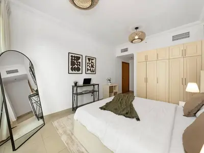a white bedroom with a bed and a mirror at Spacious Home in the heart of Marina w Seaview in Dubai