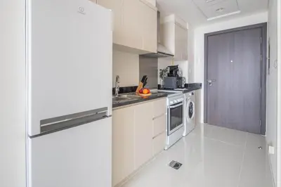 a kitchen with white cabinets and a refrigerator at Frank Porter - Damac Carson B in Dubai