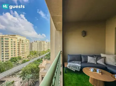 a living room with a couch and a table on a balcony at Higuests - Luxurious 2BR Haven in Iconic Palm Jumeirah in Dubai