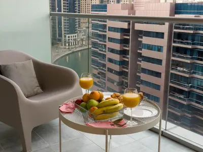 a table with a bowl of fruit and two glasses of orange juice at Bel appartement Dubai marina in Dubai