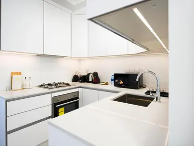 a white kitchen with white cabinets and a sink at EasyGo - Modern STU- Luma22- JVC in Dubai