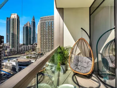 a balcony with a rattan chair and a view of a city at Premium 1 BDR, In Burj Khalifa Park, Dubai Mall Walking Distance , Opera House 1mn away in Dubai