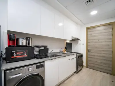 a kitchen with a washing machine and a sink at Bright JVC Studio - Serenity Escape in Dubai