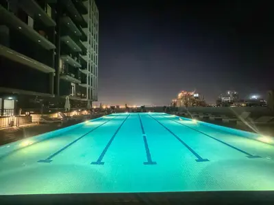 a large swimming pool at night with buildings at Bright JVC Studio - Serenity Escape in Dubai