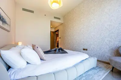 a white bed with white pillows in a room at New 2 Bedroom apartment overlooking Burj Khalifa and fountain view in downtown in Dubai