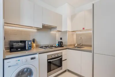 a white kitchen with a washer and a microwave at STAY BY LATINEM Luxury 1BR Holiday Home CV B207 near Burj Khalifa in Dubai