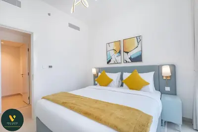 a bedroom with a large white bed with yellow pillows at Vogue Downtown Views II with Direct Access to Dubai Mall Via a Climate Controlled Bridge, Two Bedroom Apartment with Balcony and Burj Khalifa View in Dubai