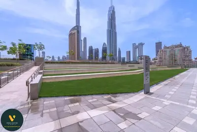 a park with benches and grass in front of a city at Vogue Downtown Views II with Direct Access to Dubai Mall Via a Climate Controlled Bridge, Two Bedroom Apartment with Balcony and Burj Khalifa View in Dubai