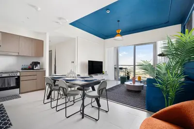 a kitchen and dining room with a blue ceiling at Arthouse Grande Signature - 2 BR with Full Burj Khalifa and Fountain View in Dubai