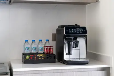 a coffee maker and water bottles on a counter at Arthouse Grande Signature - 2 BR with Full Burj Khalifa and Fountain View in Dubai